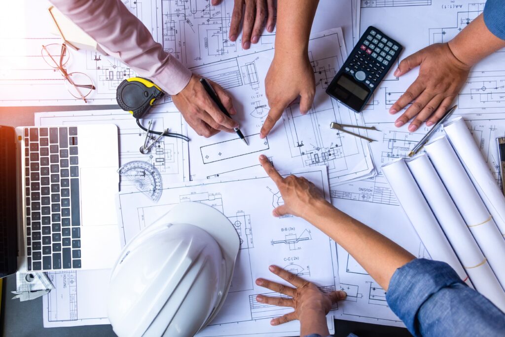 Plans papier de chantier, des mains indique des informations sur les documents
