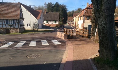 Photo d'une route dans un village, avec un pont aménager pour les piétions